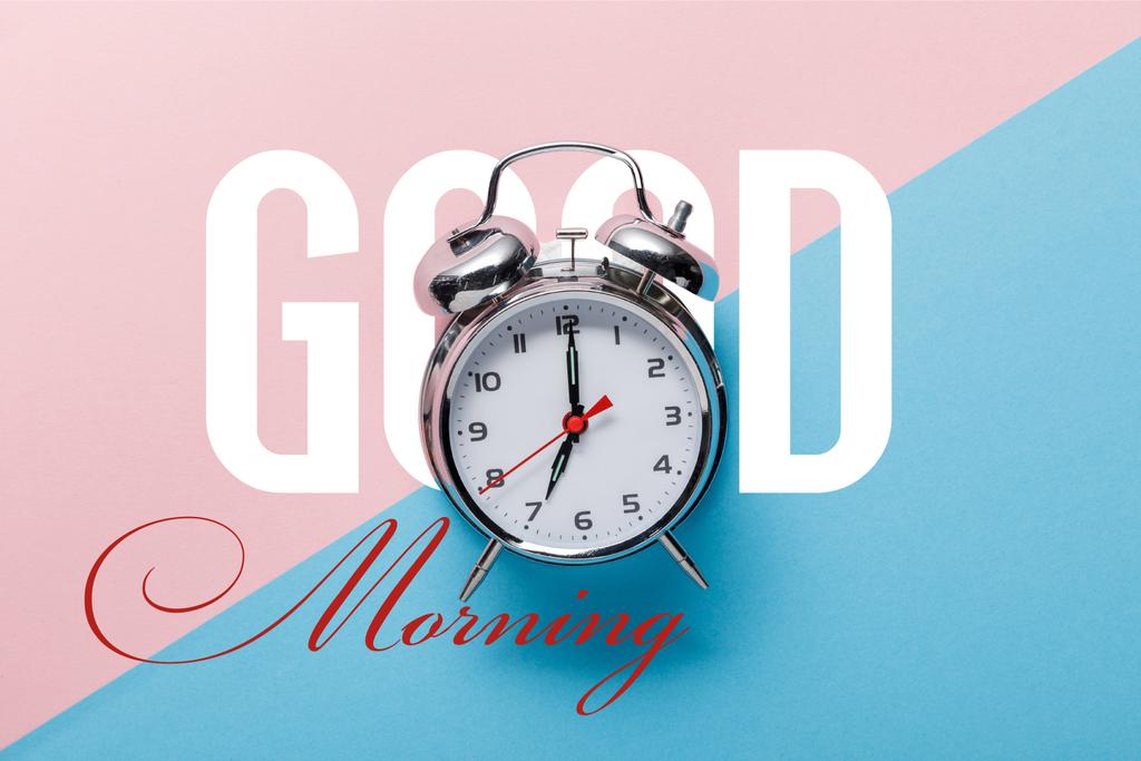 vista superior del reloj despertador clásico plateado sobre fondo rosa y azul con letras de buena mañana
 - Foto, imagen