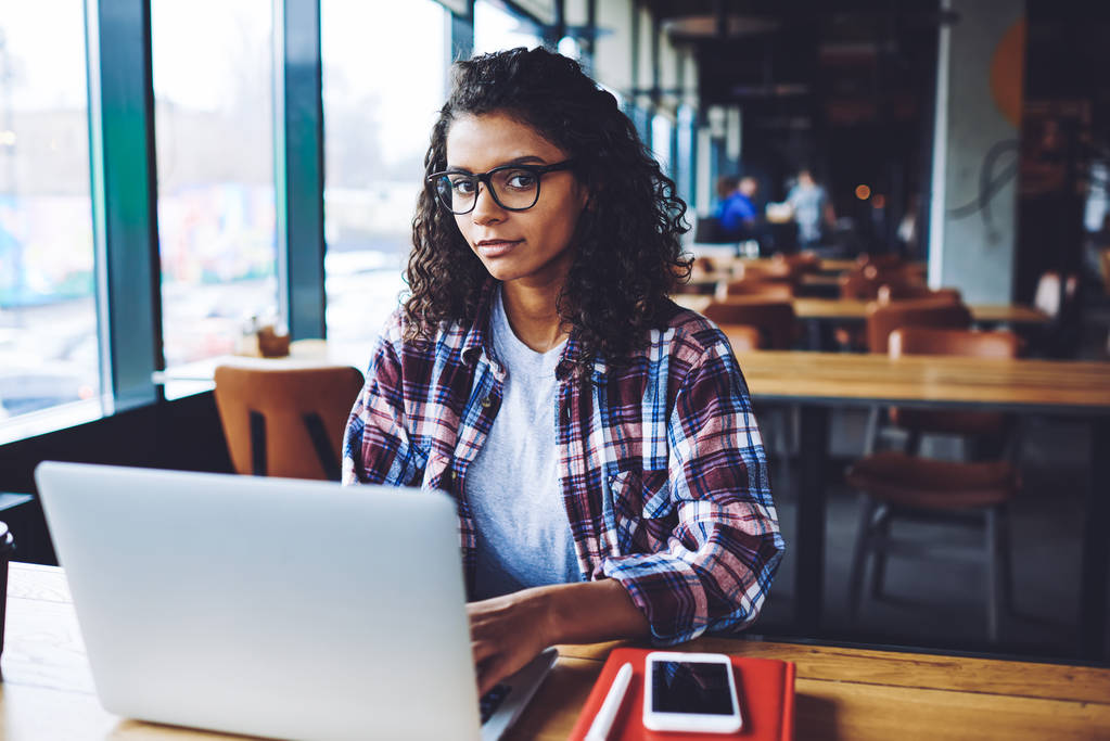 Portrait de femme noire attrayante dans les lunettes en utilisant une connexion Internet 4g pour communiquer avec les abonnés dans le réseau social assis avec un nouvel ordinateur sur le campus universitaire, concept de génération
 - Photo, image