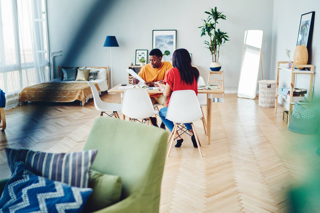 Africký americký pár sedí u stolu s dokumenty a mluví o rodinném rozpočtu, tmavé kůže žena a muž tráví čas v moderním bytě diskutovat plány a kreativní nápady pro domov - Fotografie, Obrázek