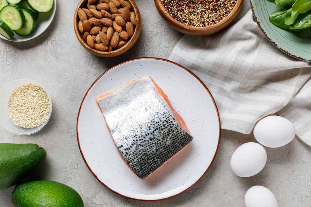 vue du dessus du saumon cru frais sur assiette blanche près des noix, légumes verts et oeufs, menu diététique cétogène
 - Photo, image