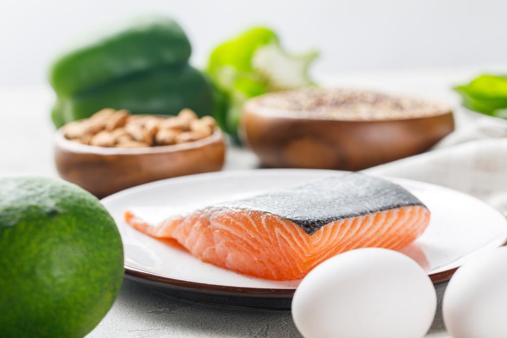 селективный фокус свежего сырого лосося на белой тарелке возле авокадо и яиц, кетогенное диетическое меню
 - Фото, изображение