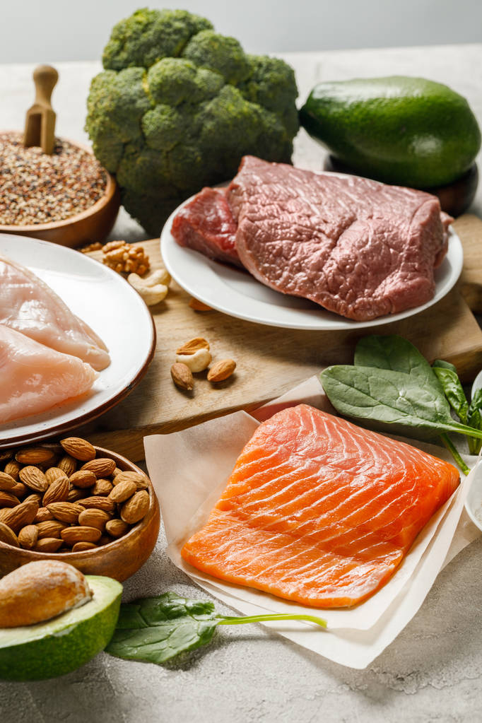 salmón crudo fresco, pechugas de pollo y carne cerca de nueces, brócoli y aguacate, menú dietético cetogénico
 - Foto, imagen