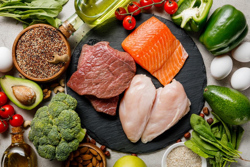 Top zicht op rauw vlees en vis tussen verse groenten, ketogeen dieetmenu - Foto, afbeelding
