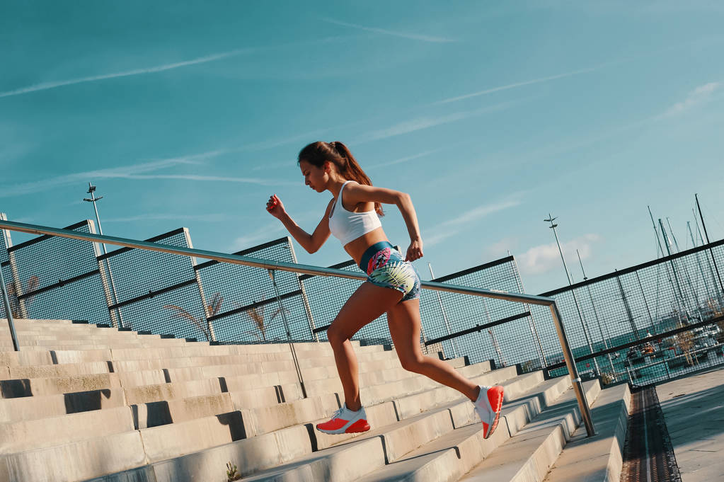 Longitud completa de la hermosa mujer joven en ropa deportiva corriendo mientras hace ejercicio al aire libre
 - Foto, Imagen