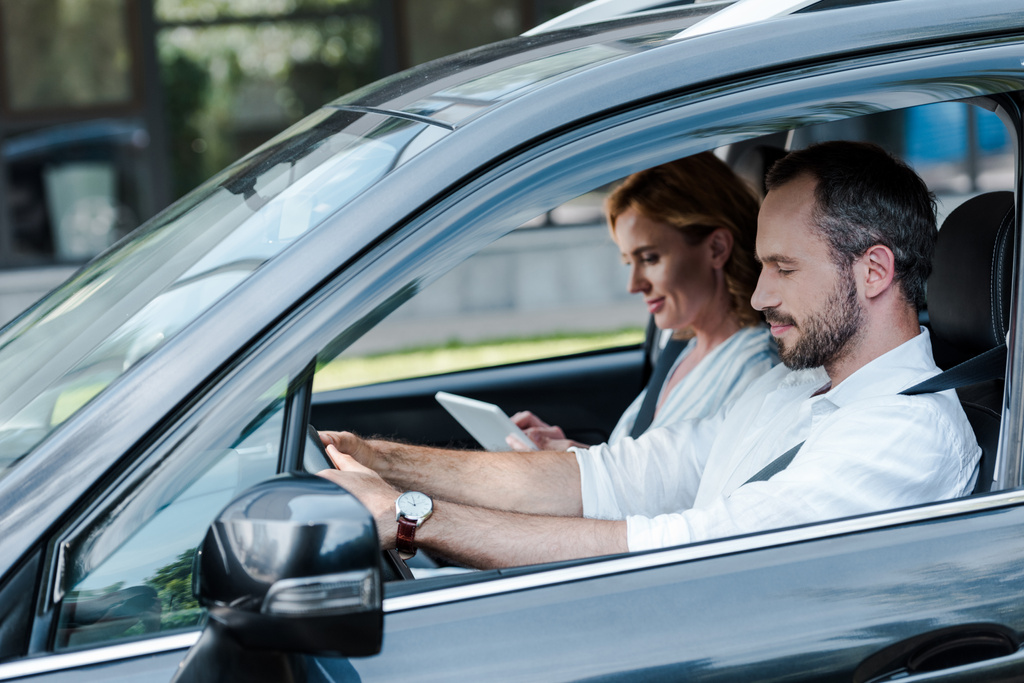 Mann fährt Auto, Frau nutzt digitales Tablet - Foto, Bild