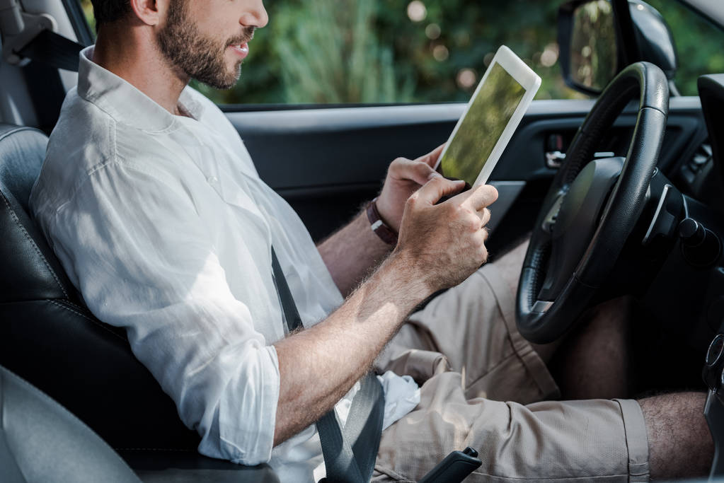 vista ritagliata di uomo barbuto seduto in auto e utilizzando tablet digitale
  - Foto, immagini