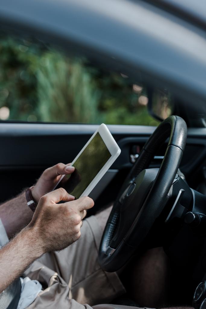 περικομμένη όψη του ανθρώπου που κατέχει ψηφιακό δισκίο και κάθεται στο αυτοκίνητο  - Φωτογραφία, εικόνα