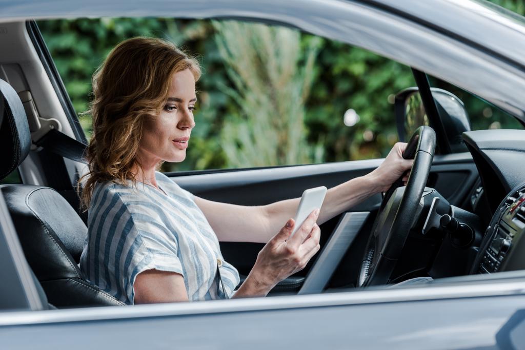 selektivní zaměření přitažlivé ženy pomocí telefonu Smartphone při jízdě autem  - Fotografie, Obrázek