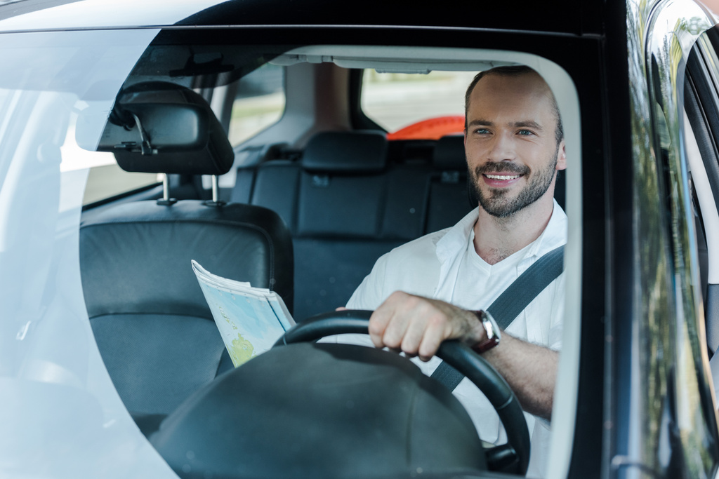 επιλεκτική εστίαση του ευτυχισμένο άνθρωπο οδήγηση αυτοκίνητο και κρατώντας χάρτη  - Φωτογραφία, εικόνα