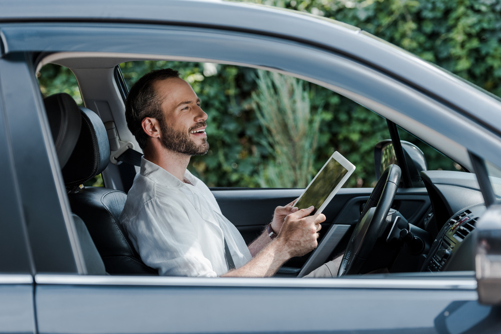 Gelukkig bebaarde man zitten in de auto en het gebruik van digitale Tablet  - Foto, afbeelding