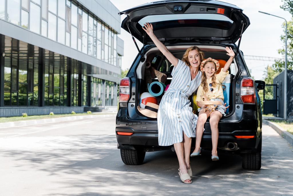 araba yakınında uzanmış elleri ile mutlu anne ve kızı  - Fotoğraf, Görsel