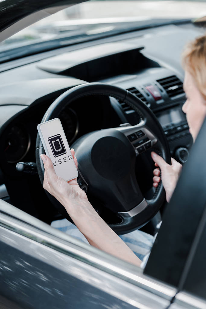 KYIV, UCRANIA - 26 de junio de 2019: vista recortada de la mujer sosteniendo el teléfono inteligente con la aplicación uber en la pantalla en el coche
  - Foto, Imagen
