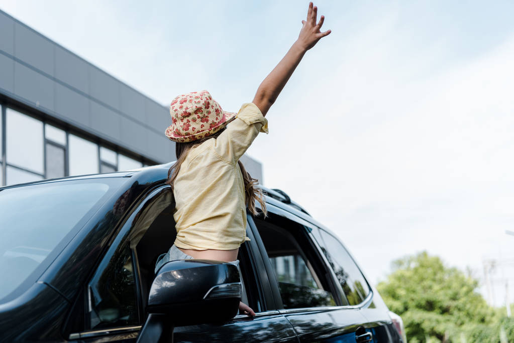 low angle view of kid with outstretched hand in car window  - Photo, Image