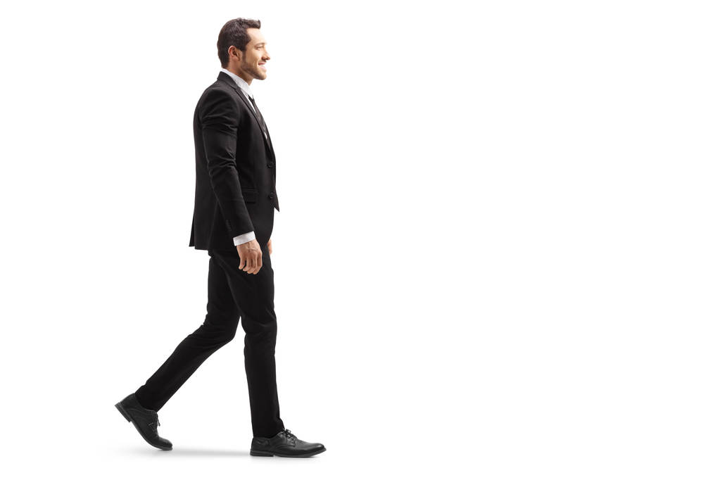Full length shot of a young man in a suit walking and smiling isolated on white background - Photo, Image