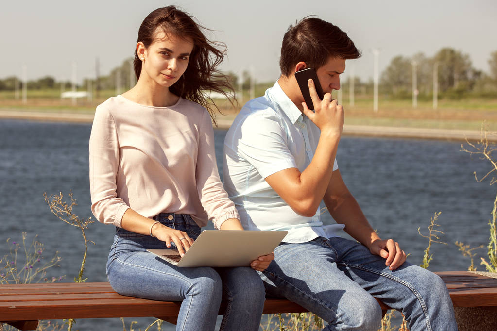 Couple utilisant un ordinateur portable à l'extérieur et regardant heureux
 - Photo, image