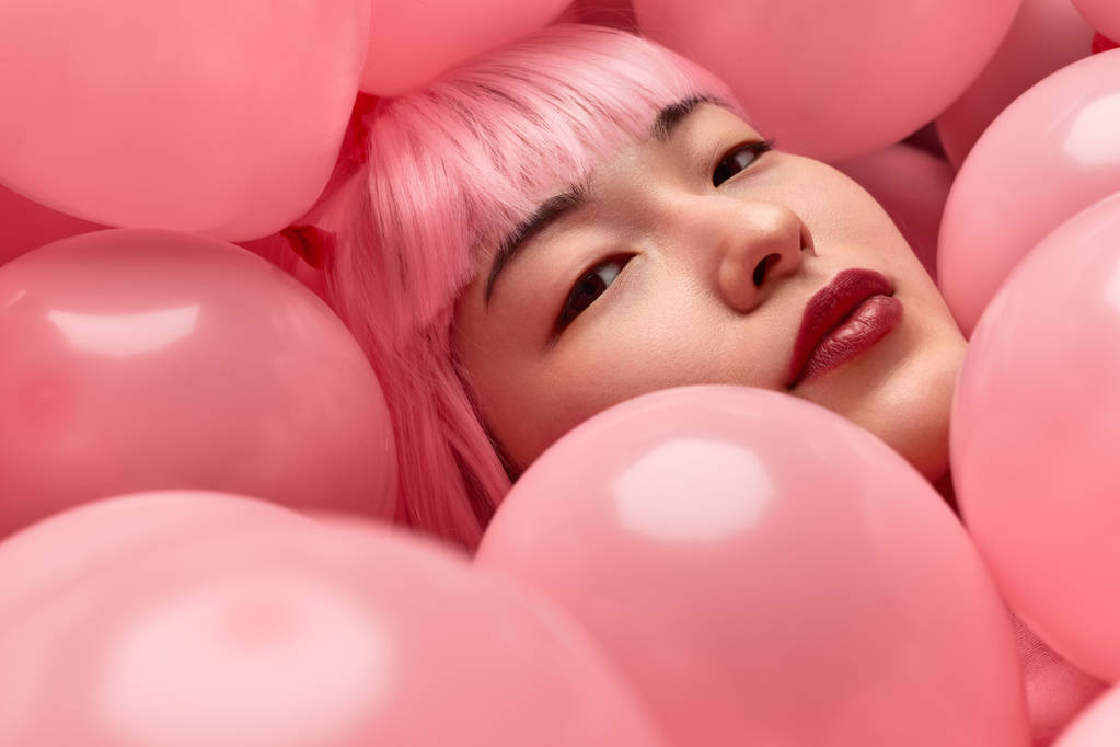 Mulher asiática atraente em peruca rosa sob balões
 - Foto, Imagem
