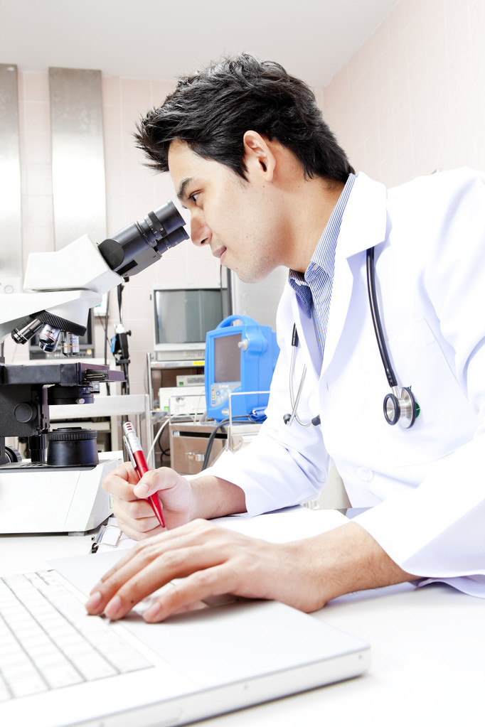 lähikuva lääkäristä hänen työpöytänsä ääressä tietokoneen edessä
 - Valokuva, kuva