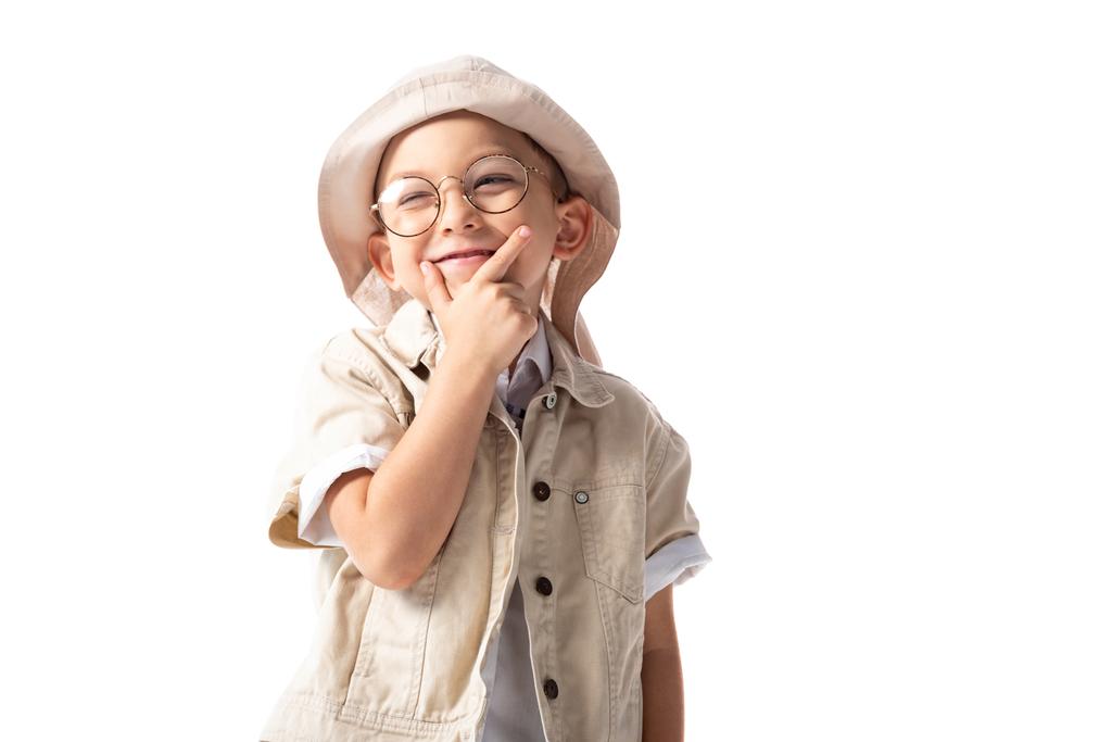 σκεπτικός εξερευνητής αγόρι σε γυαλιά και καπέλο αγγίζοντας το πηγούνι και κοιτάζοντας μακριά απομονωμένη σε λευκό - Φωτογραφία, εικόνα