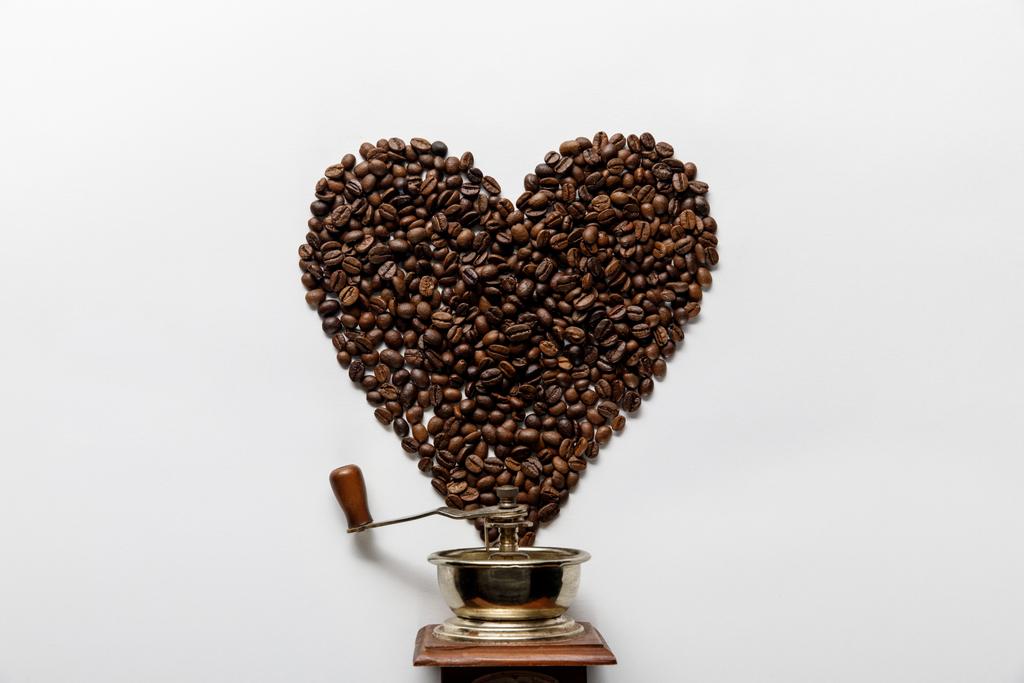 вид зверху на серце з кавових зерен біля старовинної кавоварки на білому фоні
 - Фото, зображення