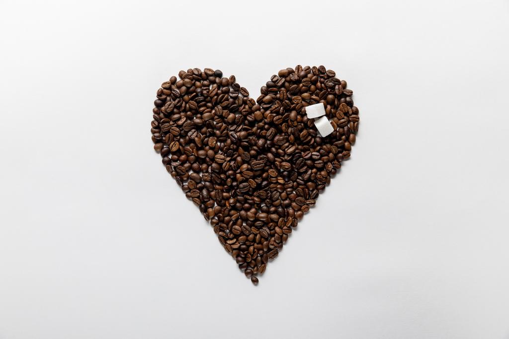 vista superior do coração feito de grãos de café com açúcar no fundo branco
 - Foto, Imagem