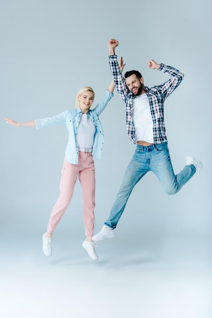 happy man and girl in casual clothes jumping on grey - Photo, Image