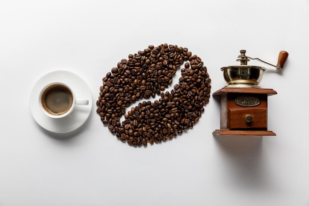 pohled na kávové zrno, šálek kávy a mlýnek na kávu na bílém pozadí - Fotografie, Obrázek