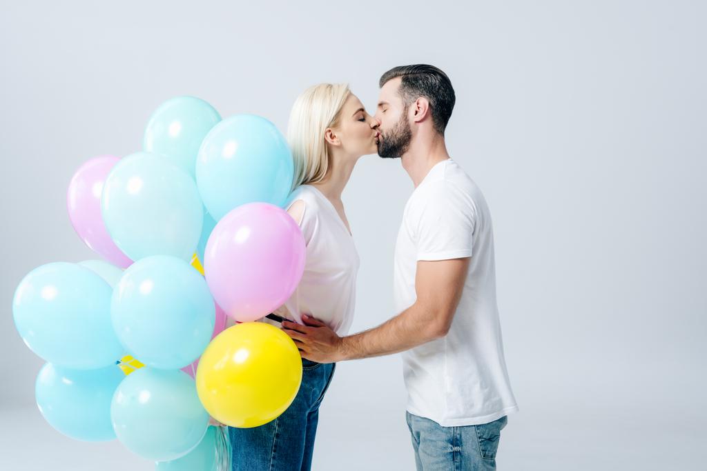 man and beautiful girl with balloons kissing isolated on grey - Photo, Image