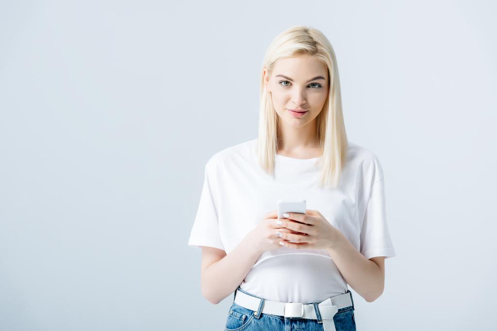 schöne blonde Mädchen mit Smartphone isoliert auf grau mit Kopierraum - Foto, Bild