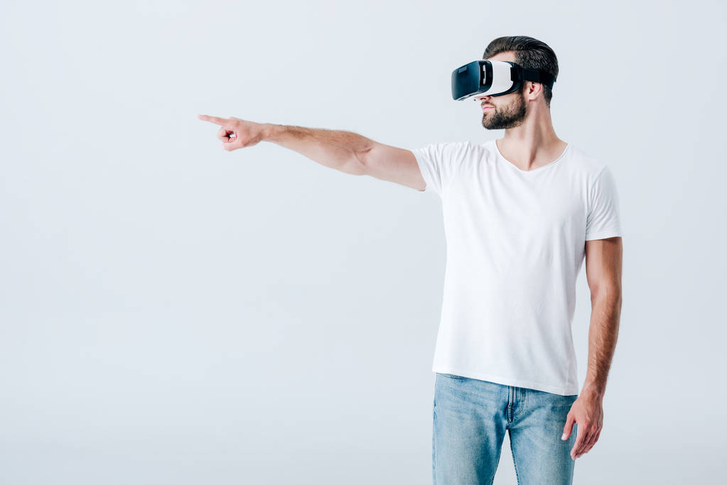 Brodatego człowieka w wirtualnej rzeczywistości słuchawki wskazujące palcem na szaro - Zdjęcie, obraz