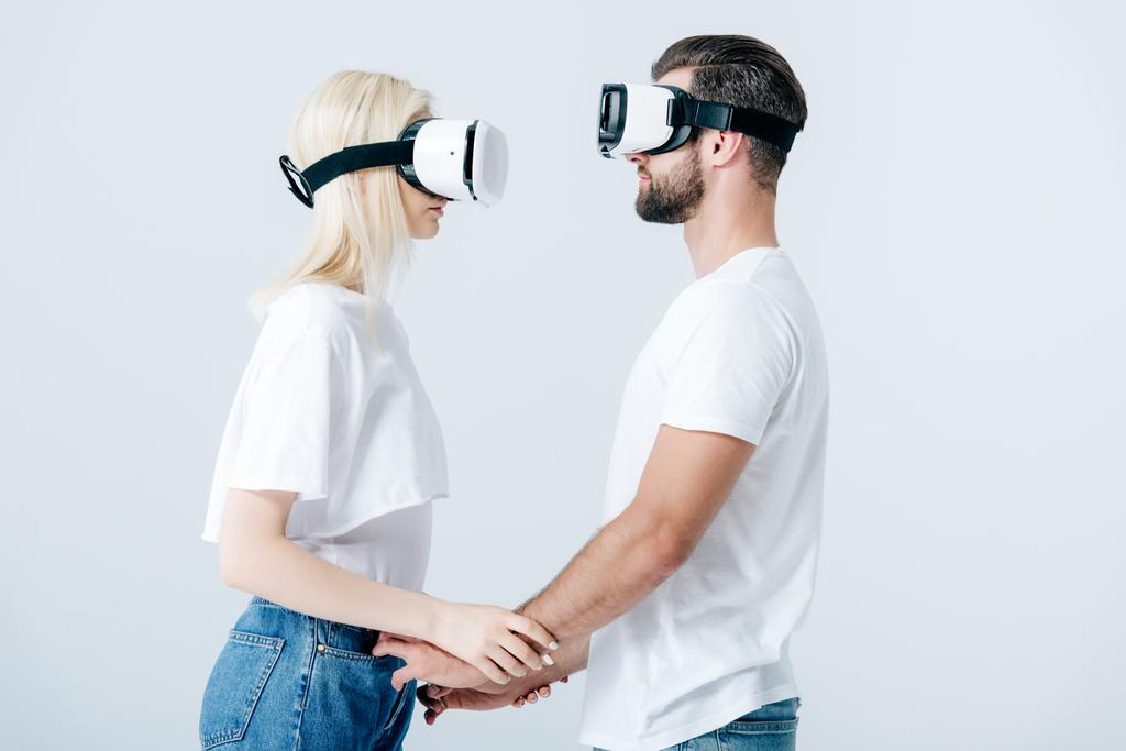 hombre y chica en auriculares de realidad virtual tomados de la mano aislados en gris
 - Foto, imagen