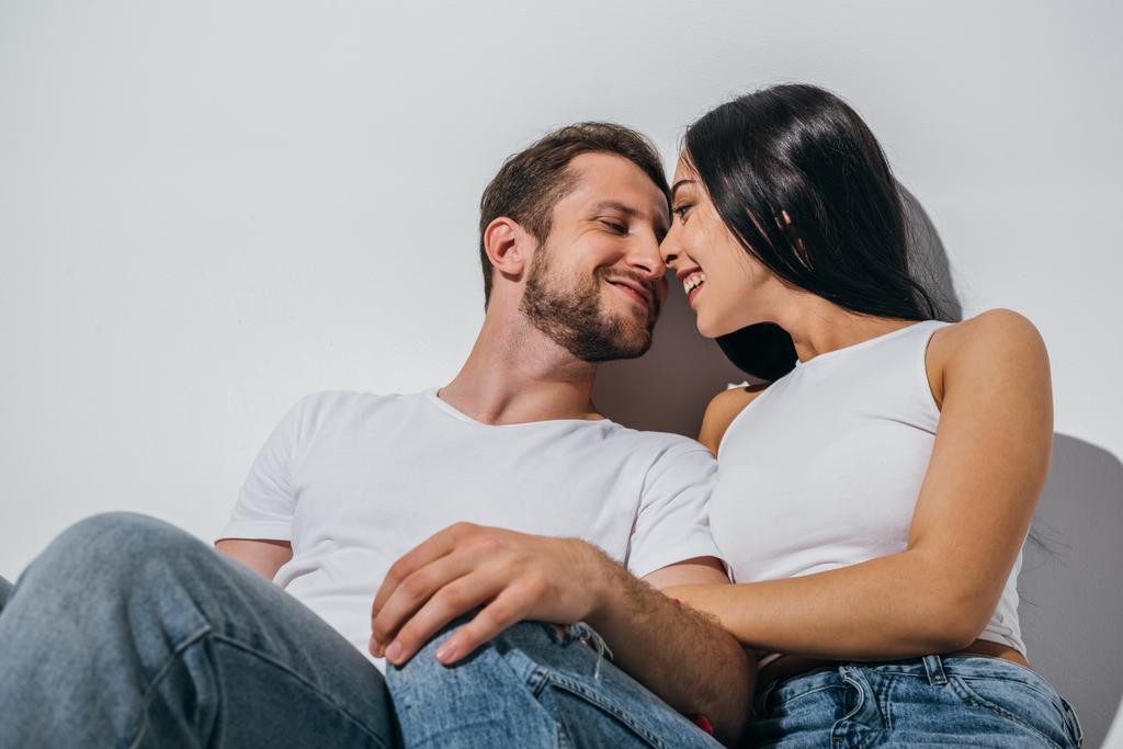 couple in love sitting on floor, smiling and looking at each other - Photo, Image