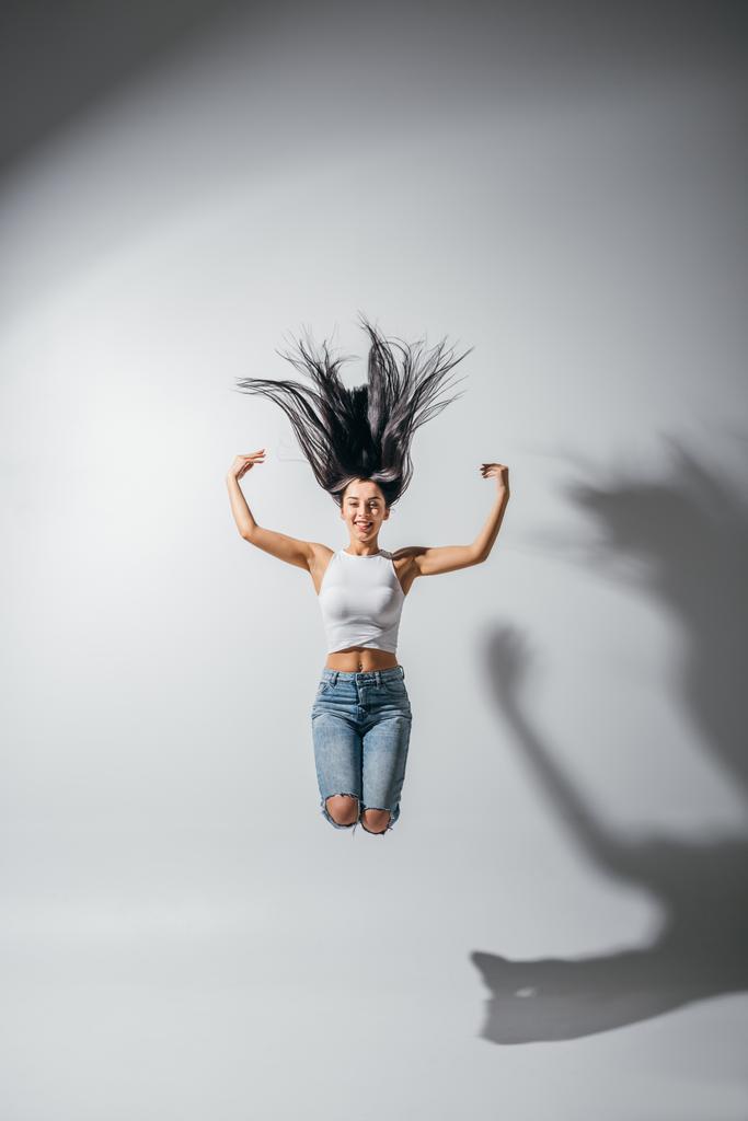 Ansicht des aufgeregten glücklichen Mädchens, das mit den Händen in der Luft springt  - Foto, Bild