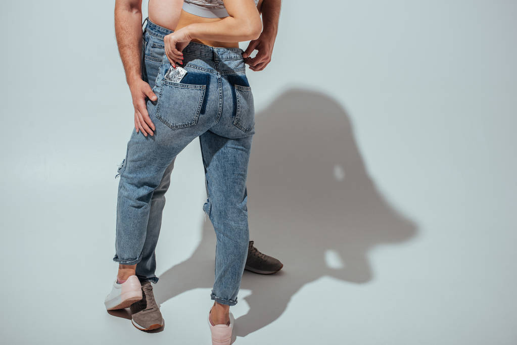 recortado vista de joven pareja abrazando mientras chica poner condón de paquete
  - Foto, imagen