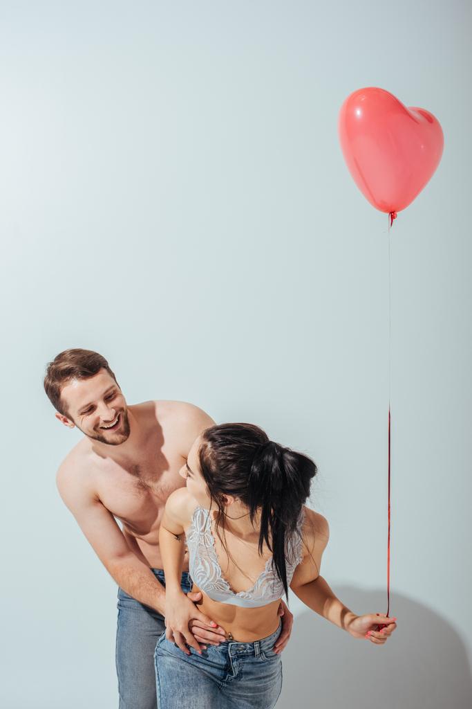casal sexy brincando uns com os outros e rindo enquanto menina segurando balão em forma de coração
  - Foto, Imagem