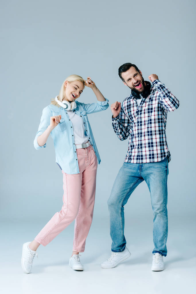 щасливий чоловік і дівчина з навушниками танцюють на сірому
 - Фото, зображення
