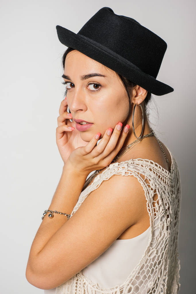 krásná dívka s černým kloboukem, který gestikulí a dívá se na kameru  - Fotografie, Obrázek