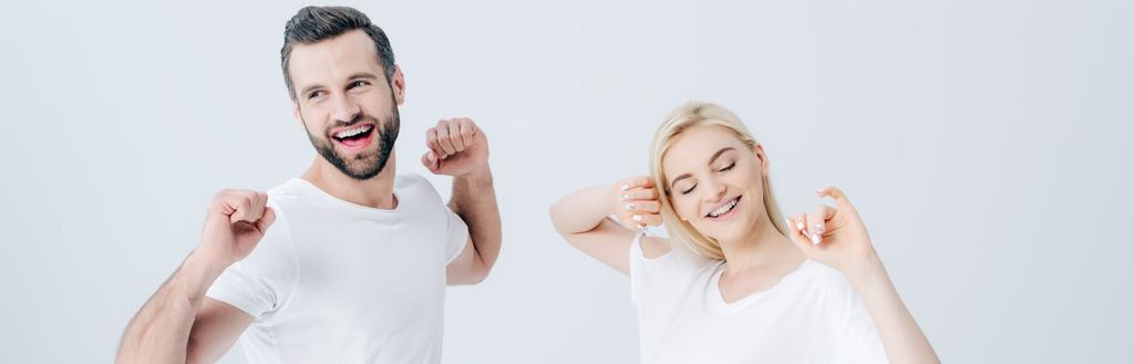 panoramic shot of happy man and young woman stretching with clenched fists isolated on grey - Photo, Image