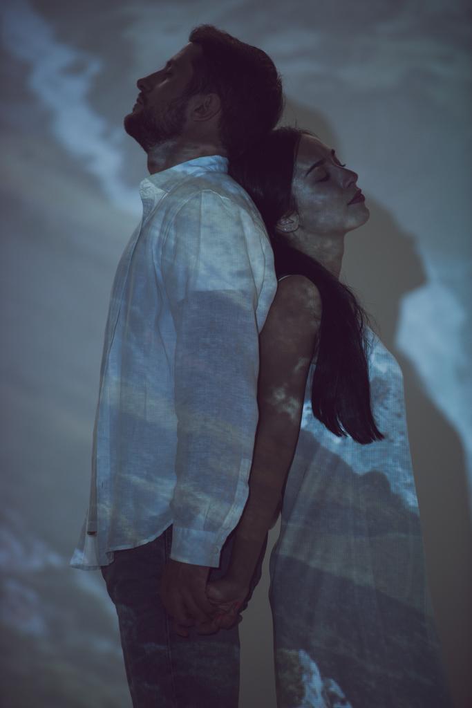 вид збоку чоловіка і дівчини, що стоїть спиною один до одного в темряві
 - Фото, зображення