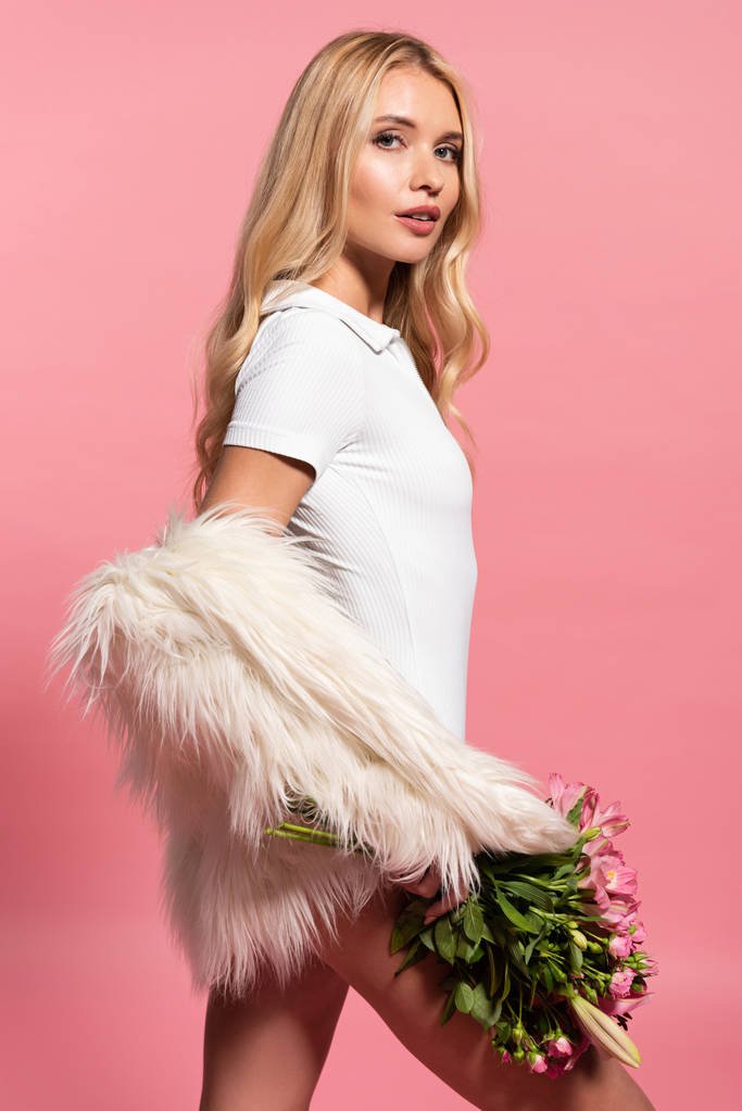 sexy krásná blondýnka v bílém umělé kožešinové bundě a v kostýmu s květinami izolovanými na růžovém - Fotografie, Obrázek