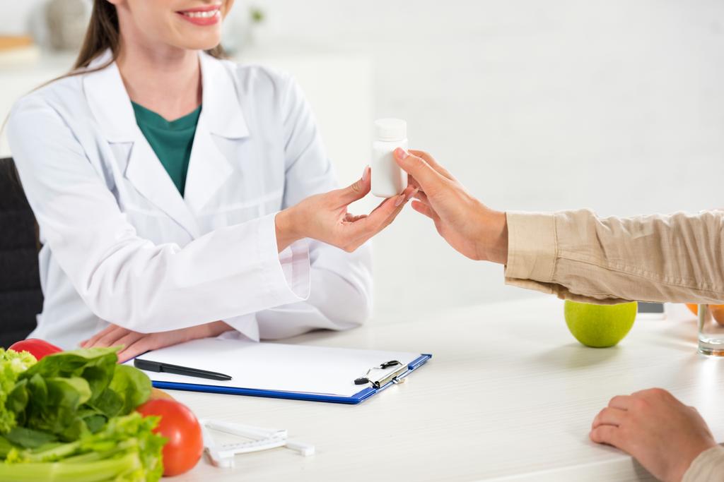 rajattu näkymä ravitsemusterapeutin antaa pillereitä potilaalle työpaikalla
 - Valokuva, kuva