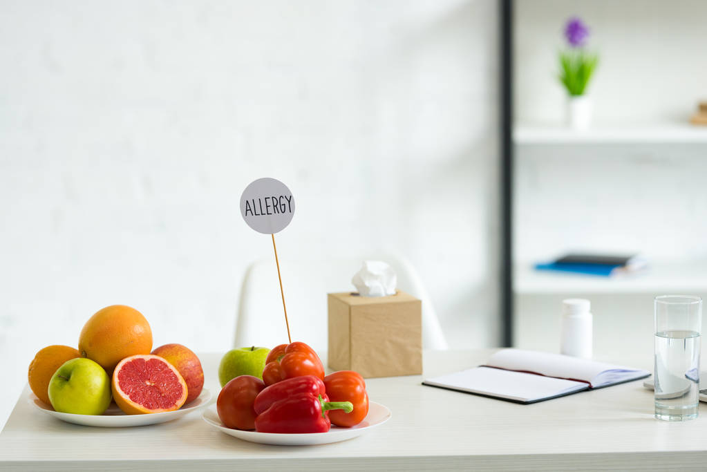 frutas frescas, legumes, copo de água, pílulas, manual e modelo com alergia à inscrição na mesa
 - Foto, Imagem