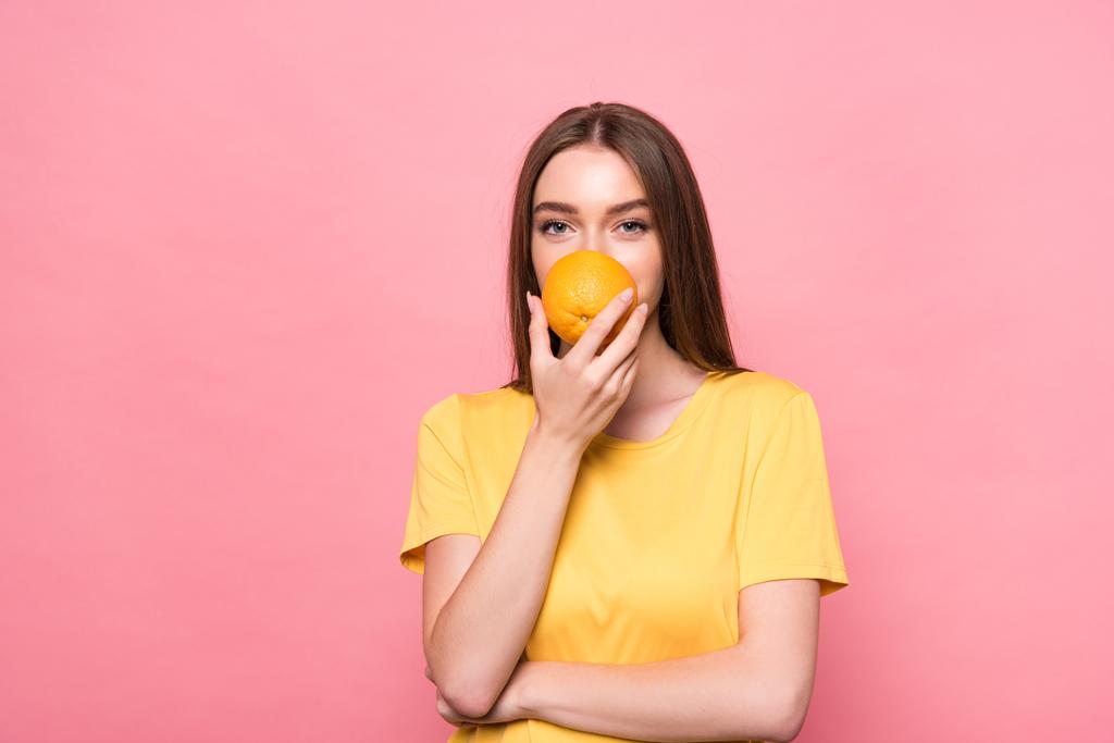 vista frontal de chica atractiva sosteniendo naranja aislado en rosa
 - Foto, Imagen
