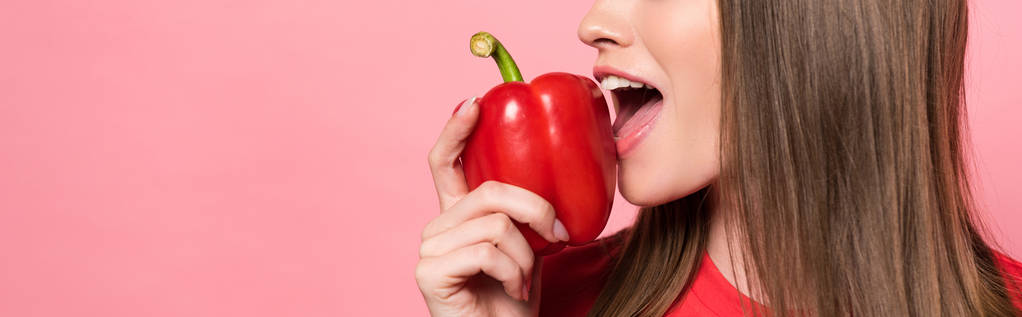 plano panorámico de mujer joven comiendo pimiento rojo aislado en rosa
 - Foto, imagen