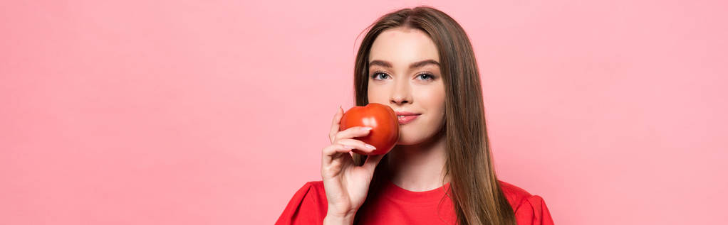 panoramic shot of young woman holding tomato and looking at camera isolated on pink - Photo, Image