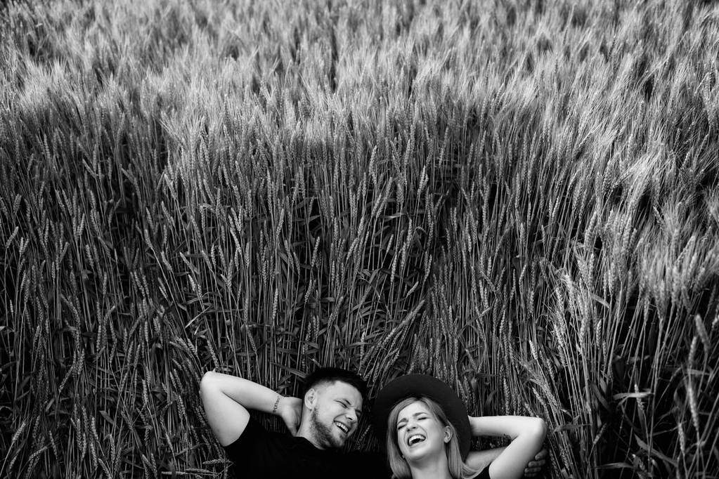 小麦畑に横たわる美しい若いカップル - 写真・画像