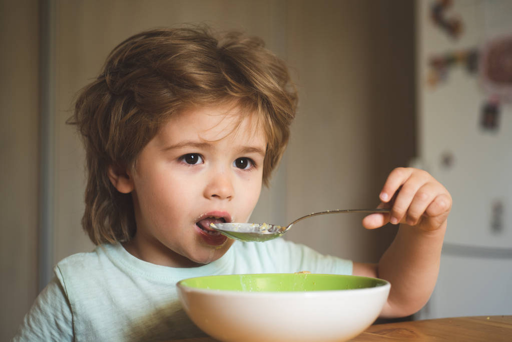 Tasty kids breakfast. Cute child eating breakfast at home. Baby eating. Good morning in Happy family. Hungry little boy eating. Happy child. Little boy having breakfast in the kitchen. - Photo, Image