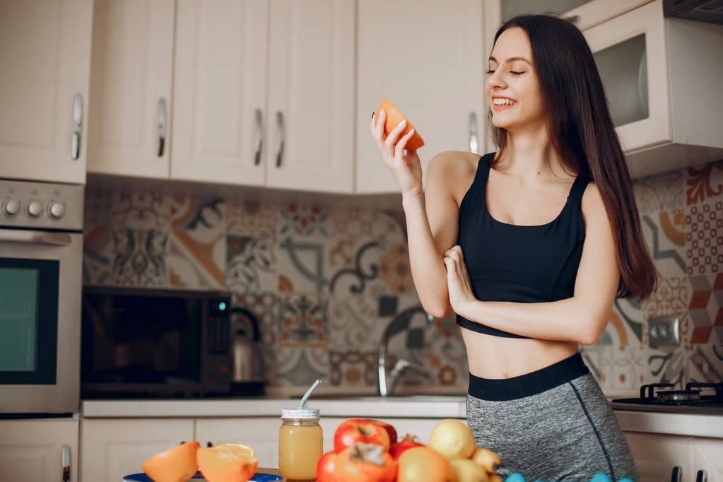 Sport fille dans une cuisine avec des fruits
 - Photo, image