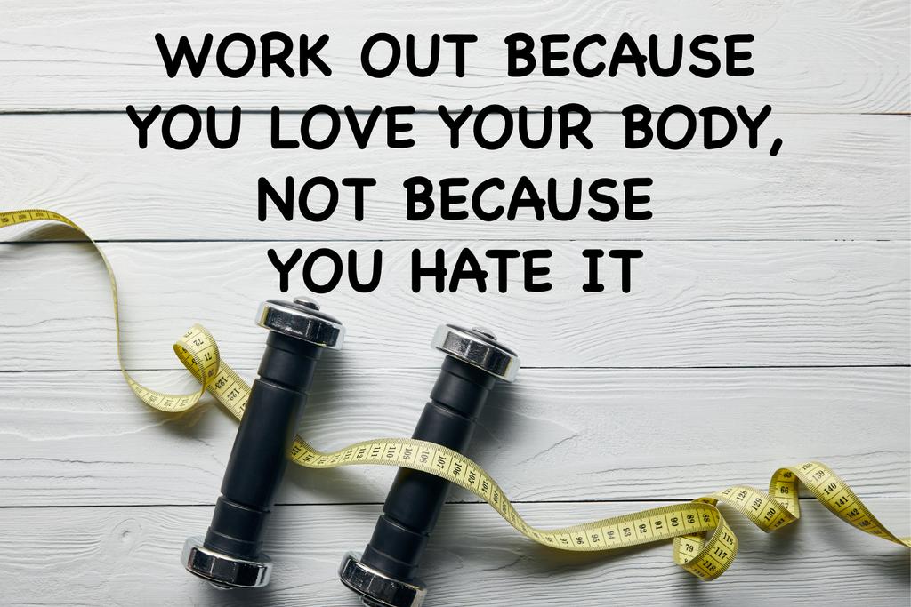 top view of measuring tape and dumbbells on wooden white background with work out because you love your body not because you hate it lettering - Photo, Image