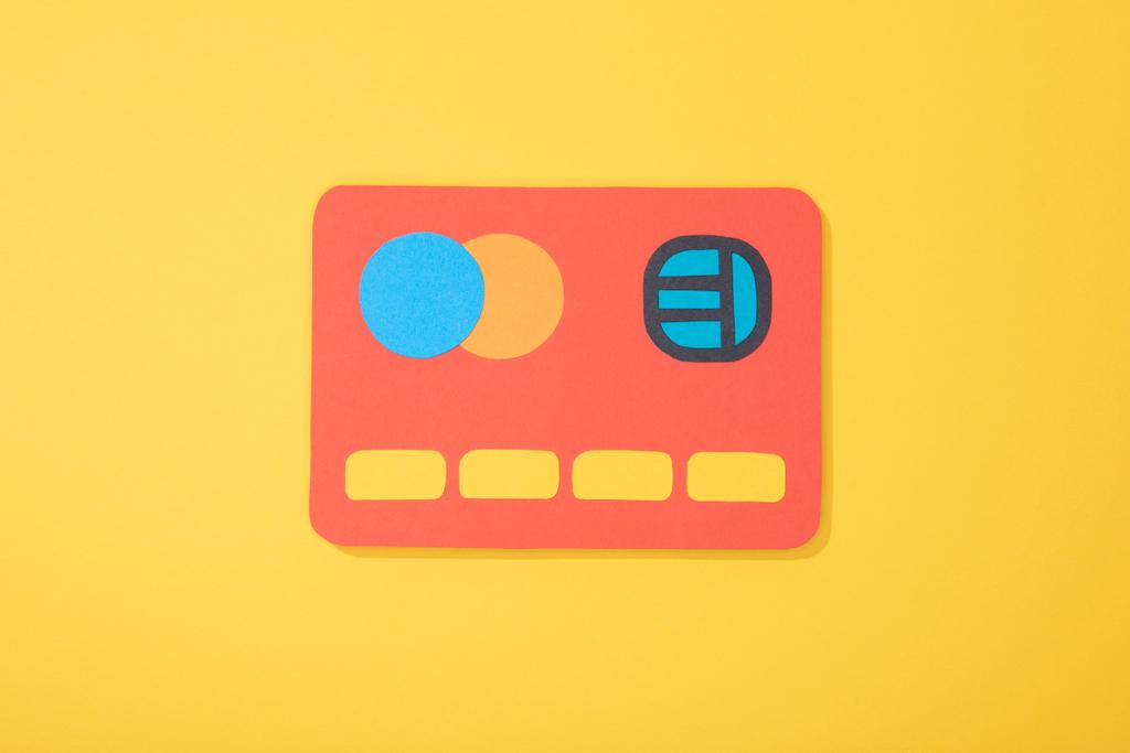 top view of red paper icon of credit card isolated on yellow  - Photo, Image