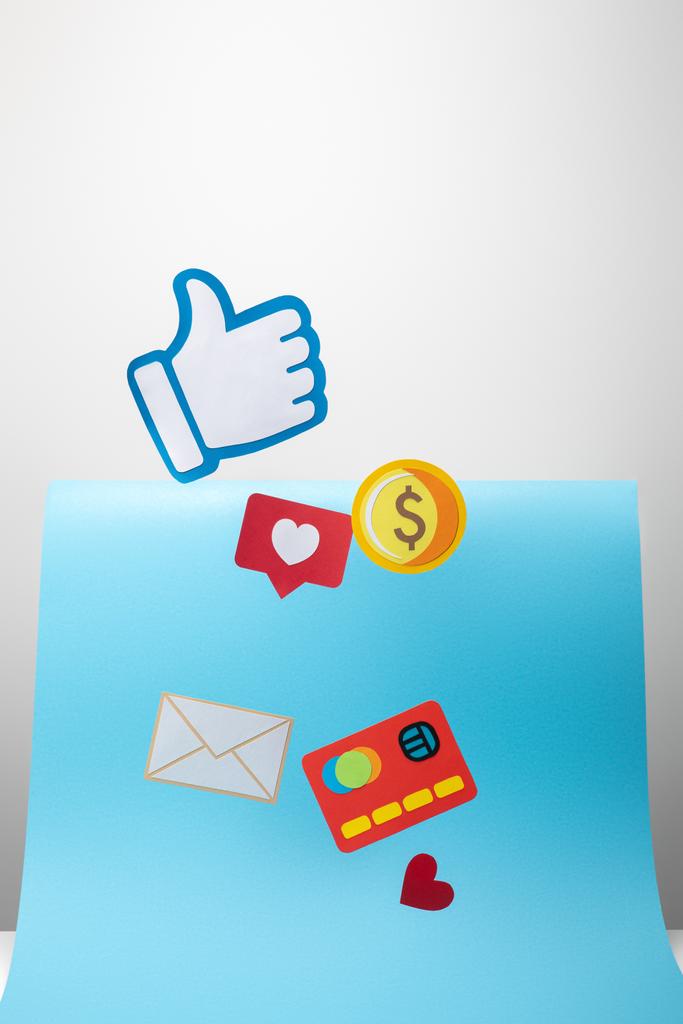 Papiersymbole mit Umschlag, Münze, Kreditkarte, Herzen und Daumen nach oben auf blauem und grauem Hintergrund - Foto, Bild